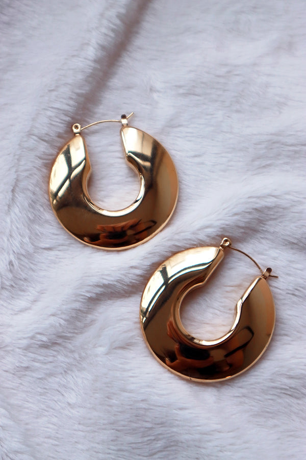 Hypoallergenic material gold hoop earrings on white cloth