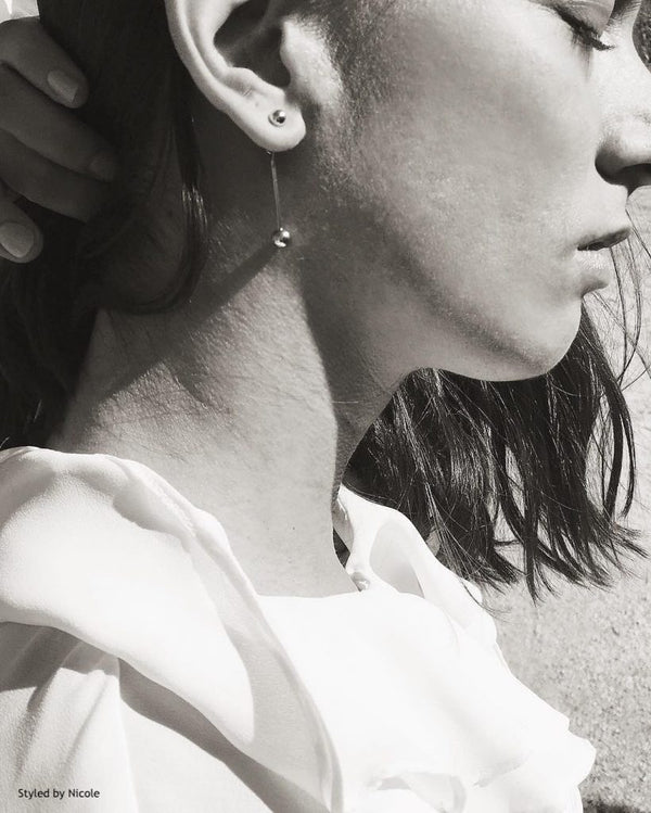 European female wearing SH and Co. Jewelry's drop earrings shot in black and white 