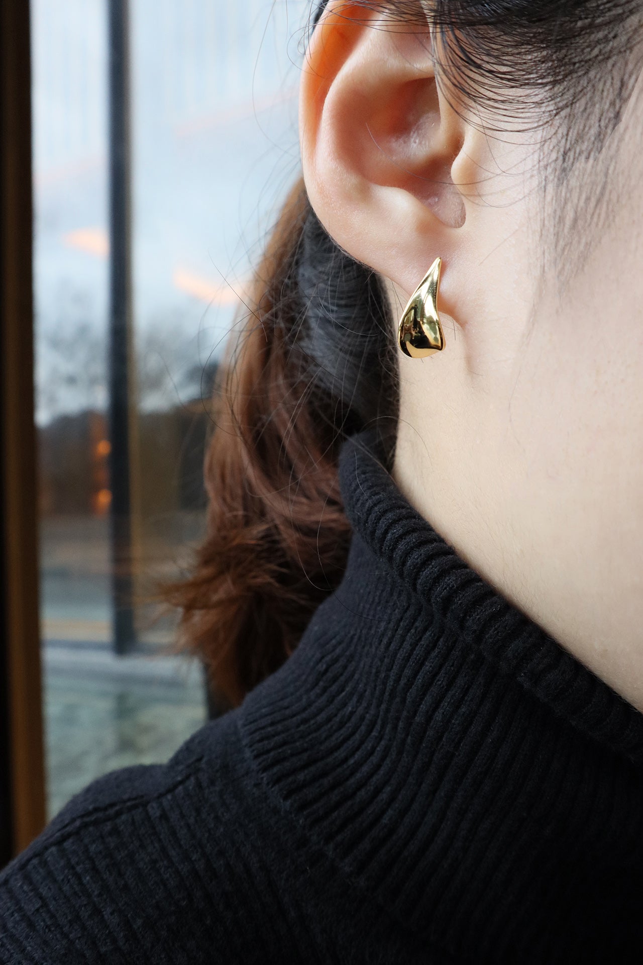 KOL wearing gold petal studs showing half her face