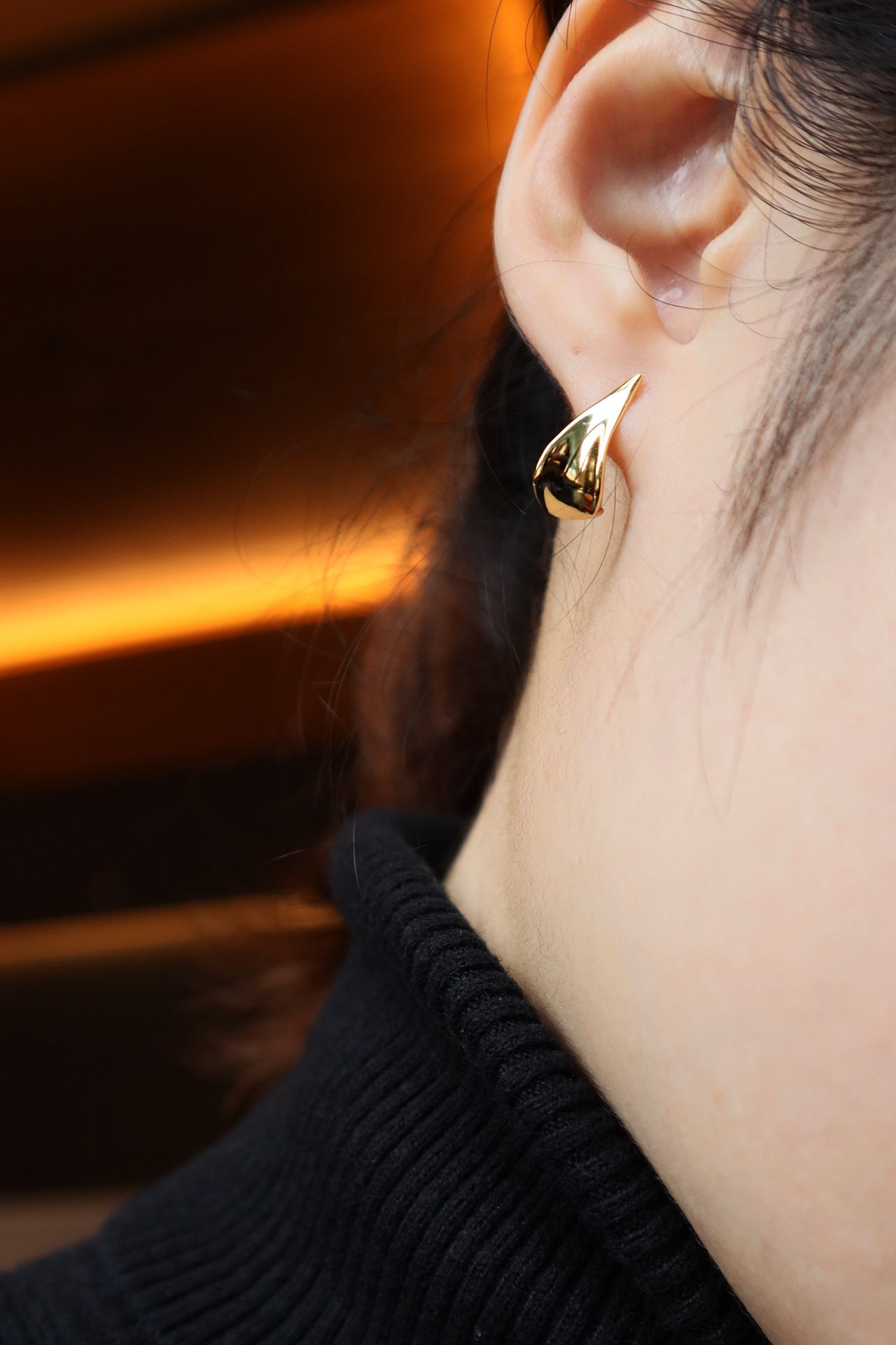 Female model in black turtleneck sweater wearing gold earrings