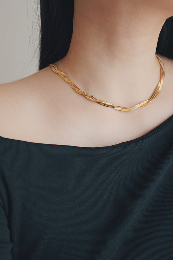 Close-up of a hypoallergenic gold snake necklace draped gracefully around a womans neck, highlighting its sleek and smooth texture.