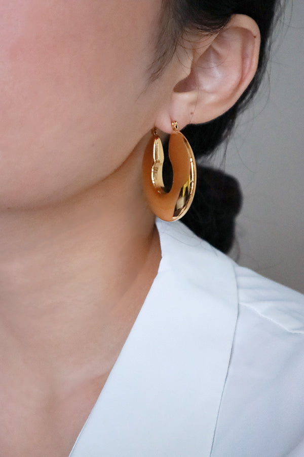 Woman showing half her face that wearing high quality gold hoops