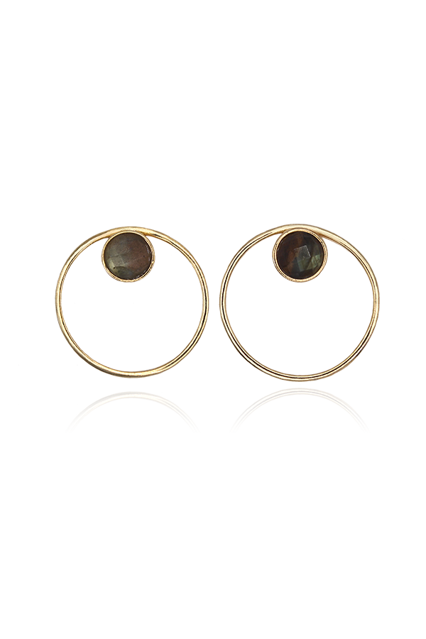 A standalone image of a pair of large, circular gold hoop earrings, each featuring a faceted, dark grey and green labradorite stone set within the top part of the circle. The earrings are displayed symmetrically on a black background with reflections below.