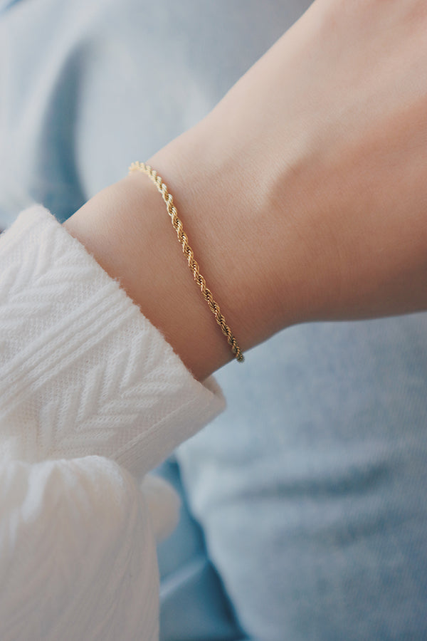 A single gold rope chain bracelet worn on a person's wrist, seen from a slight angle.