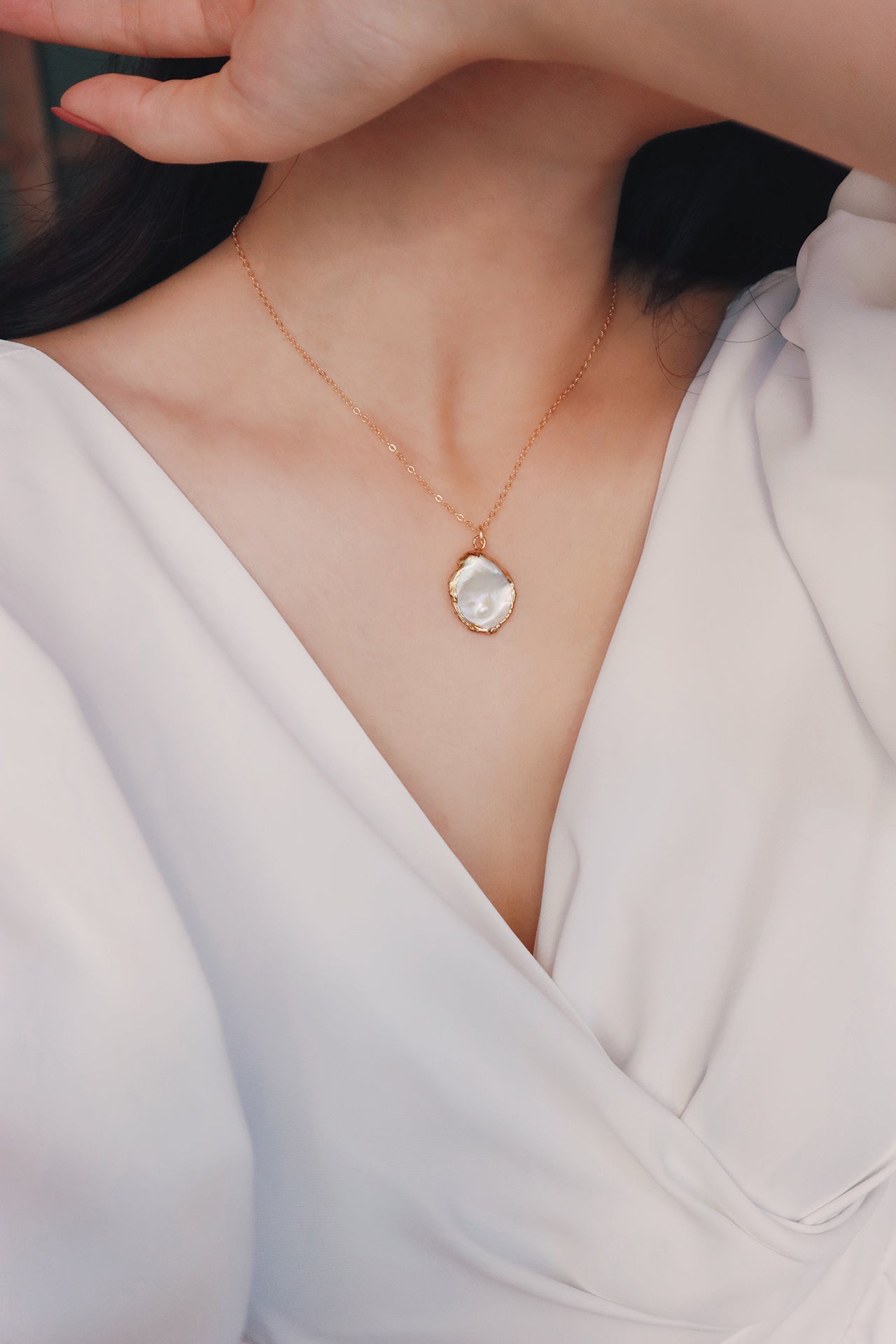 Women in white dress wearing a baroque pearl necklace