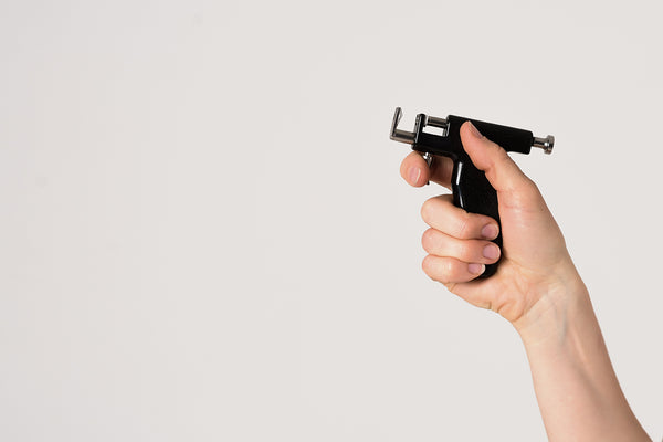 a hand holding an ear piercing gun