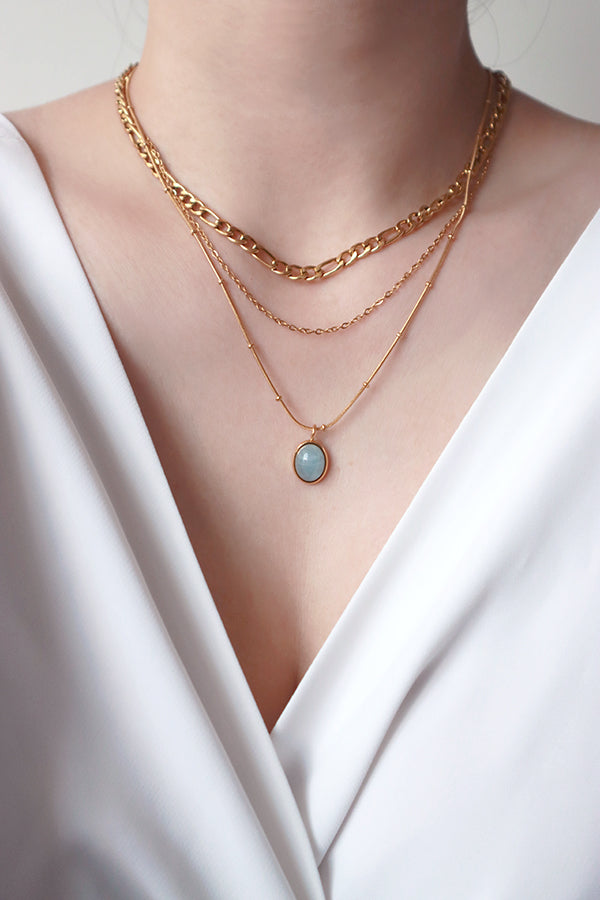 Model layering aquamarine necklace with Figaro layered necklace