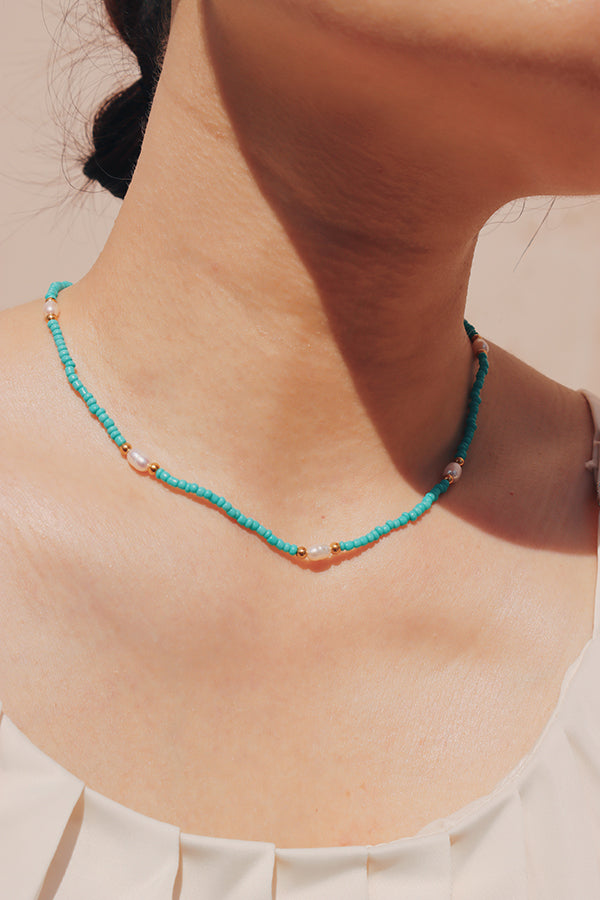 Woman wearing a blue bead and freshwater pearl choker for summer