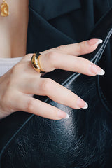 Model in black suits wearing a bold gold ring on the middle finger