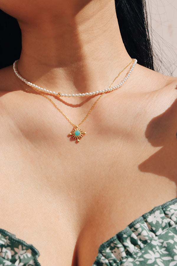 A delicate amazonite pendant necklace layered with pearls, creating a breezy vacation-inspired style.
