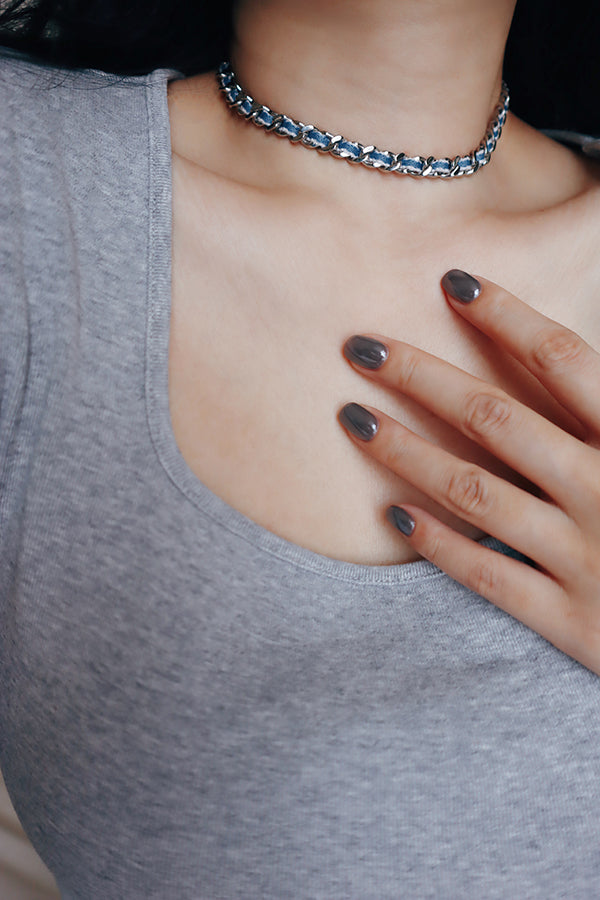 Model wearing a denim chain choker necklace styled with a grey tank top for a cool minimalist look.