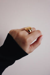 女人向鏡頭展示時髦優雅的金色寬面設計戒指