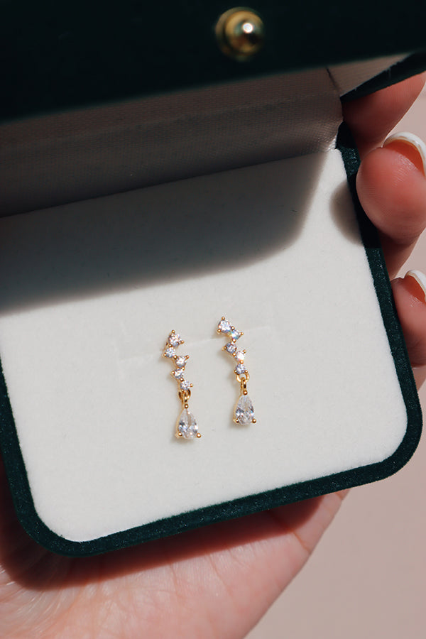 Delicate teardrop crystal earrings presented in a deep green velvet case, radiating luxury and fine jewelry aesthetics.