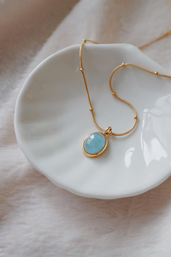 Aquamarine necklace displayed on the white porcelain plate
