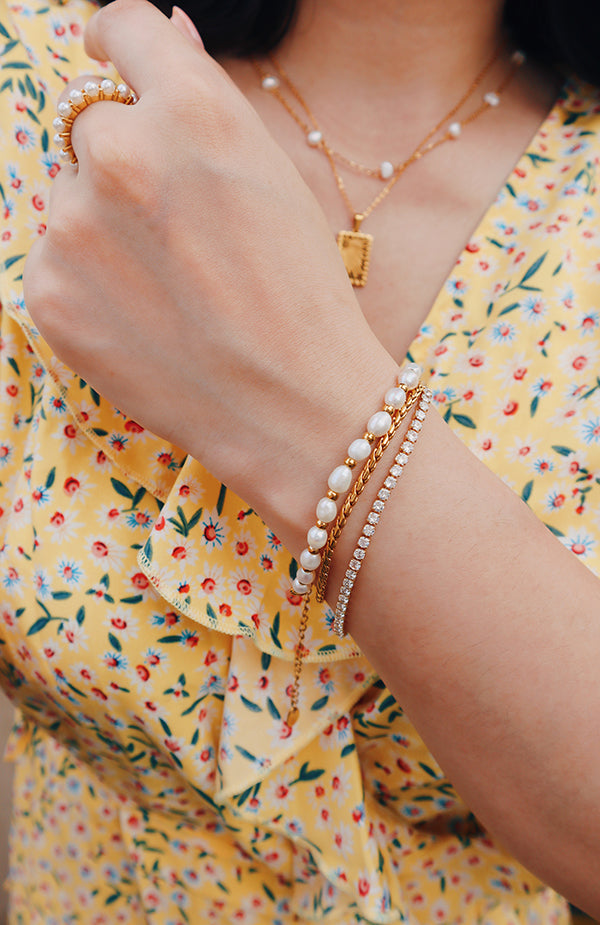 Woman in dress layering bracelets for her summer outfit