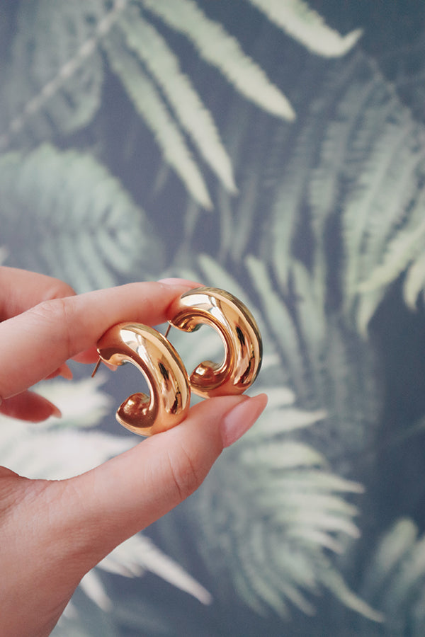Woman holding fashionable and enduring statement hoop earrings.