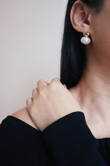 Woman in black dress paired statement pearl earrings for her night outfit