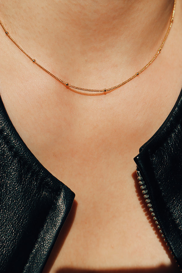 Girl in black showing her gold necklace to camera