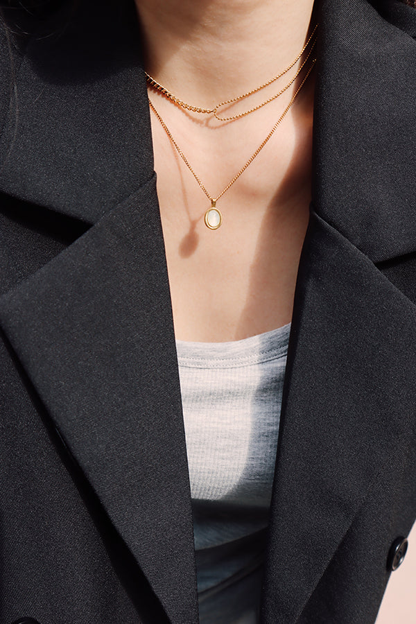 Gold layered chain necklace styled with a blazer and neutral top, delivering a chic city-ready aesthetic.
