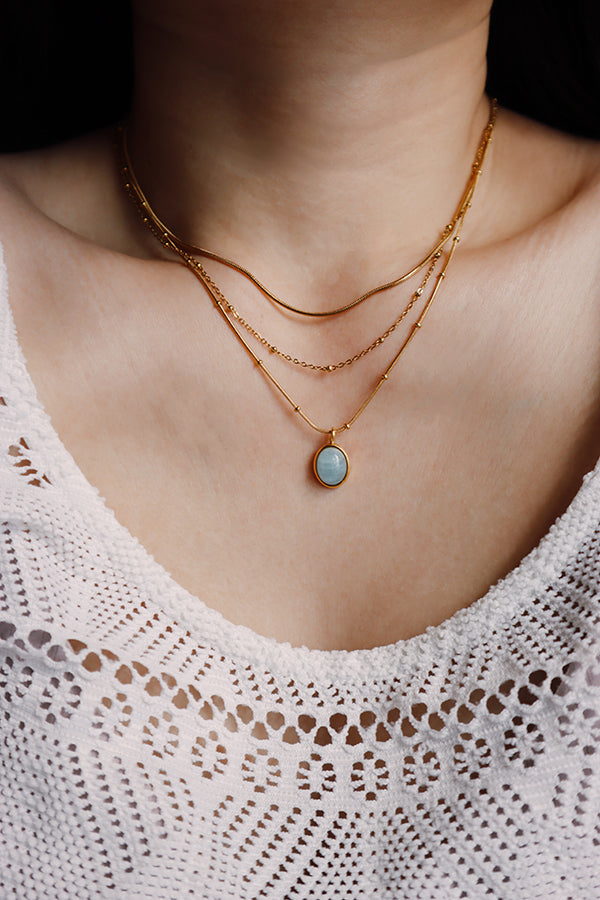 Gold layered necklace styled with a gemstone pendant chain, creating dimension and a personalized layered look.