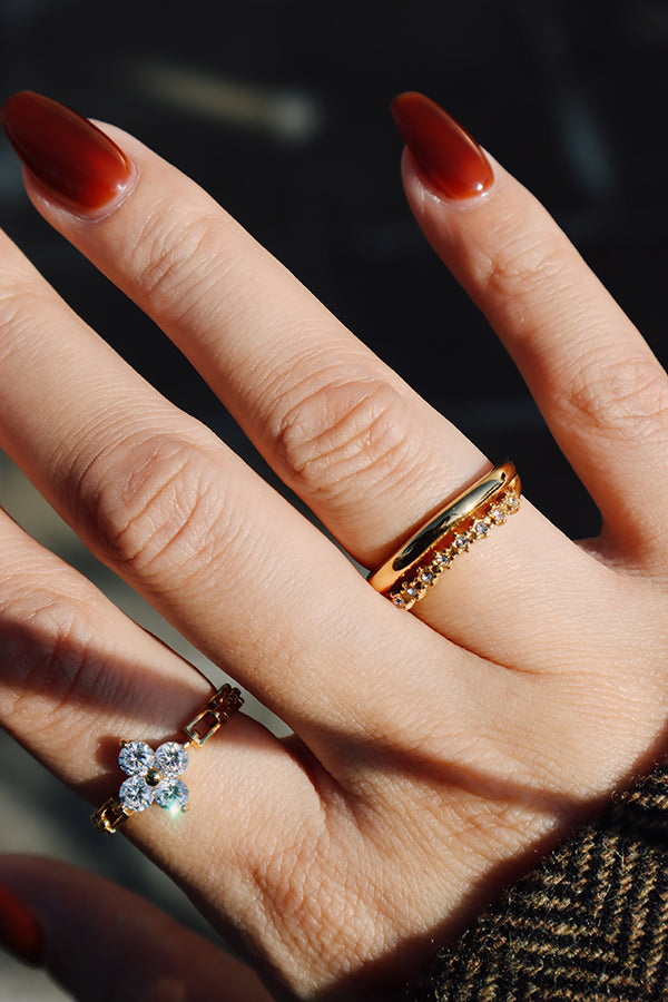 Curved zircon stacking ring layered with a floral ring, creating an elegant and dimensional look.