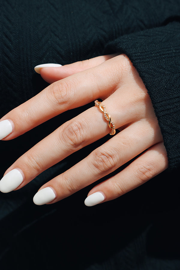 Close-up of a woman's hand adorned with a delicate gold twisted stack ring, styled with a black outfit for an elegant and timeless look.