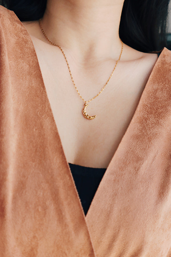 Woman in coat wearing a gold moon pendant necklace