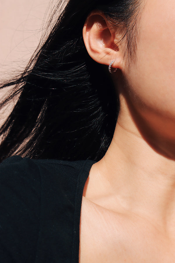 Woman showing her half face with 925 silver huggie on her ear.