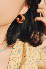 Woman wearing statement gold hoop earrings, water-resistant and hypoallergenic
