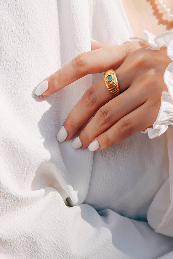 Sophisticated yet bold, this statement gold ring with a green gemstone adds a vintage charm to any outfit.
