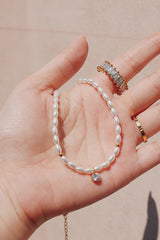 Woman holding a radiant pearl choker with round CZ pendant for a close up view