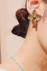 Woman wearing earrings with textured petals and radiant anyolite stone