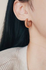Model showing her morandi color earrings to camera