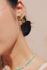 Woman is dress wearing tarnish free and waterproof flower earrings for vacation outfit
