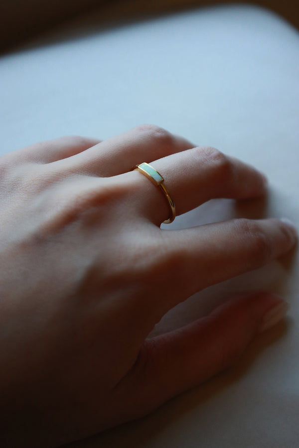 Hand of women wearing a opal gold ring on middle finger