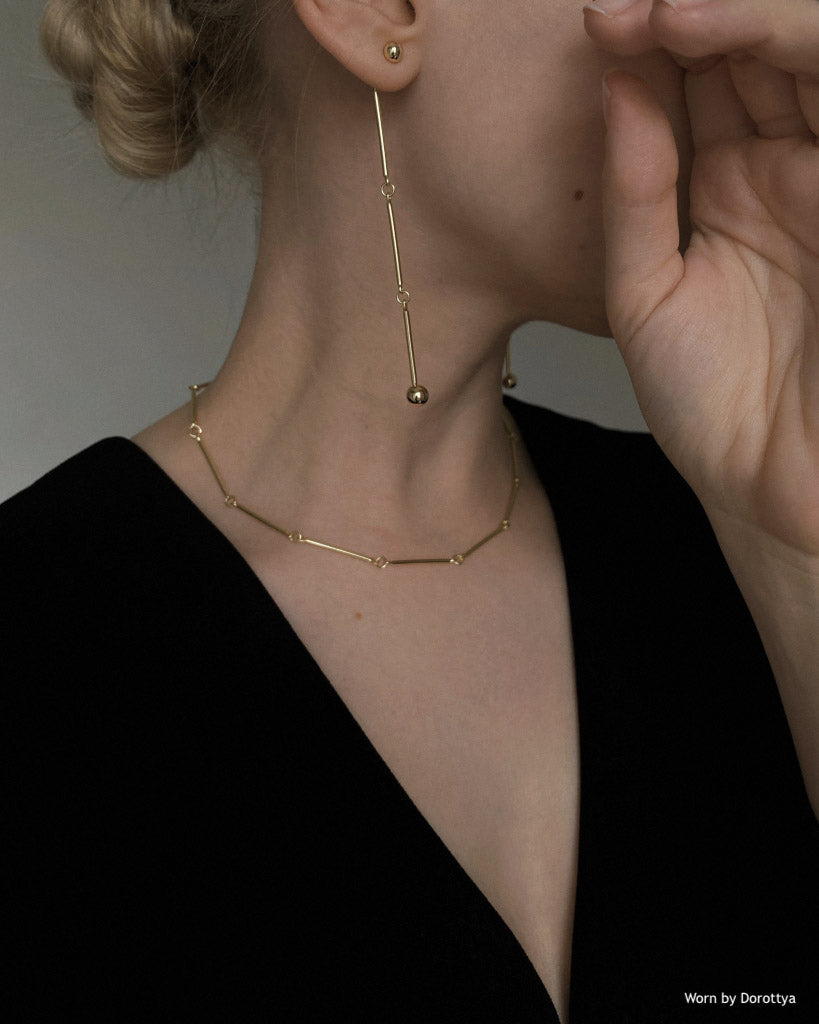 Side profile of caucasian lady wearing linked earrings and black top seen from the side