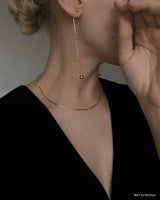 Side profile of caucasian lady wearing linked earrings and black top seen from the side