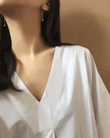 Asian female wearing a small silver drape earrings showing bottom half of her face