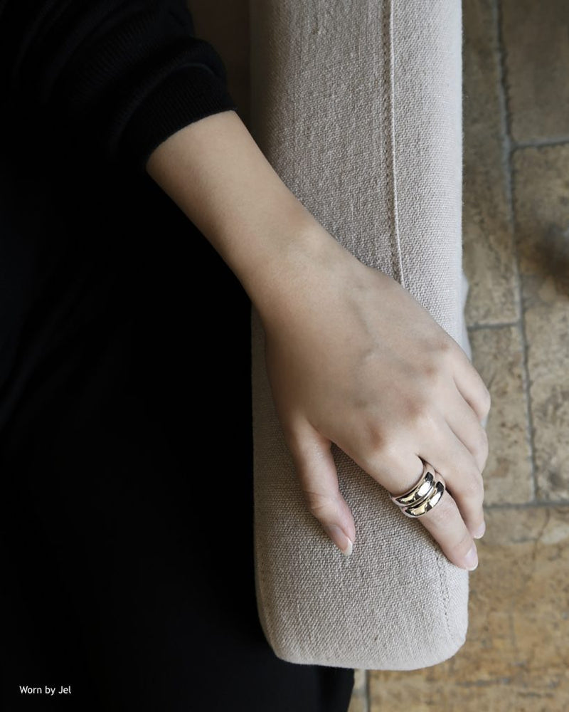 Hand model wearing stacked rings sitting on sofa