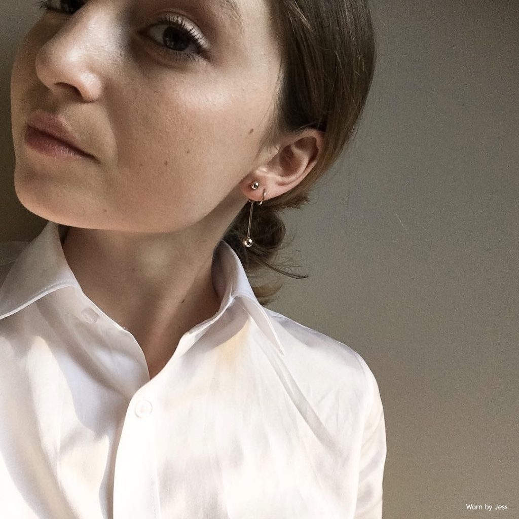 European girl wearing a white shirt and silver drop earrings from SH and Co.