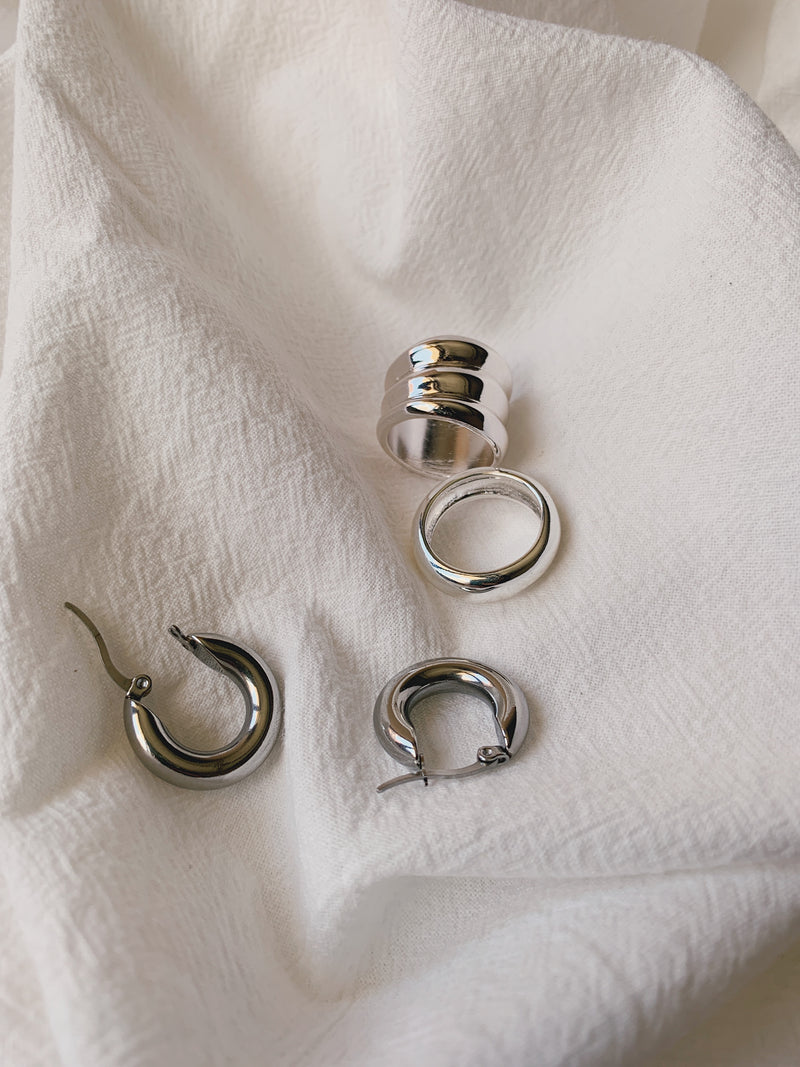 Earrings and ring laid on top of a wavy white cloth for display