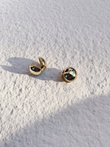 A pair of gold round small studs under sunlight