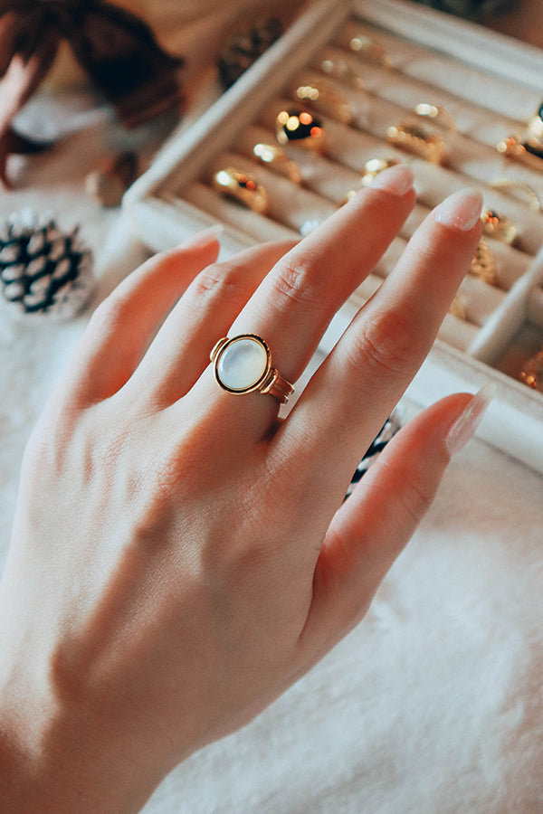 Model wearing a mother of pearl gold plated ring shows to the camera