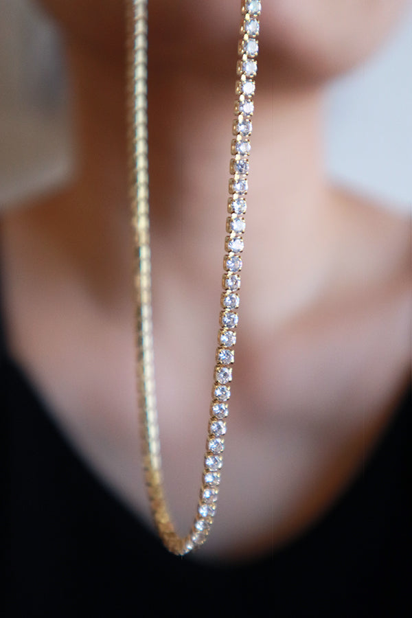 Woman showing the details of rhinestone necklace to camera