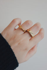 Woman showing the statement gold ring and stack ring to camera