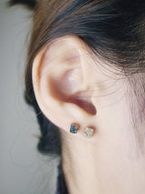 Close up of mix and match of crushed black and white diamond square studs on model