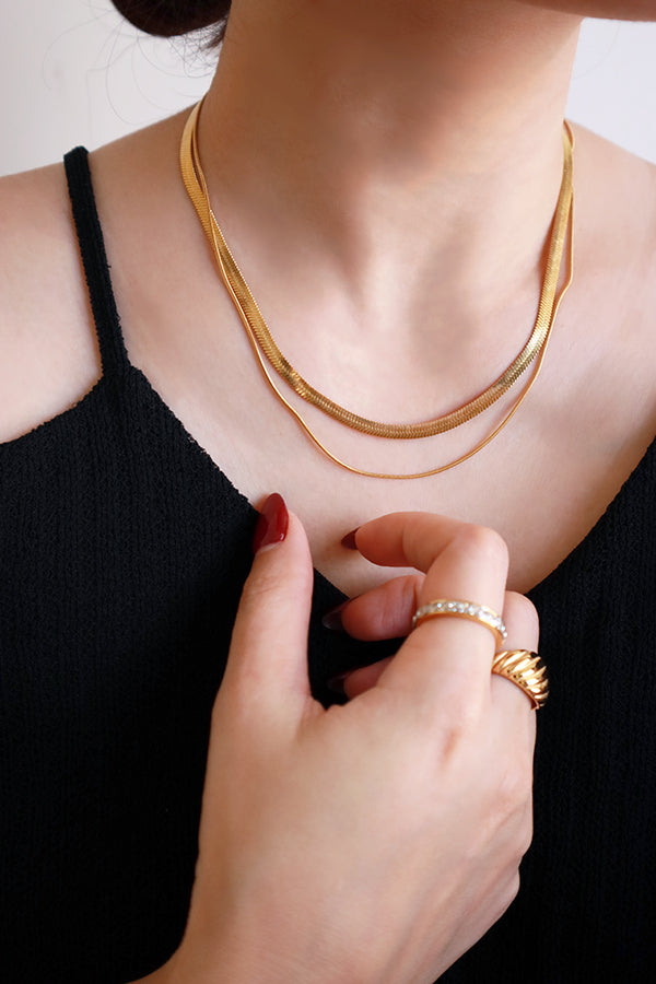 Woman in black dress with red nails wearing double layered snake chain necklace