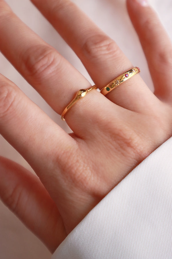Woman stacking dainty gold rings on fingers