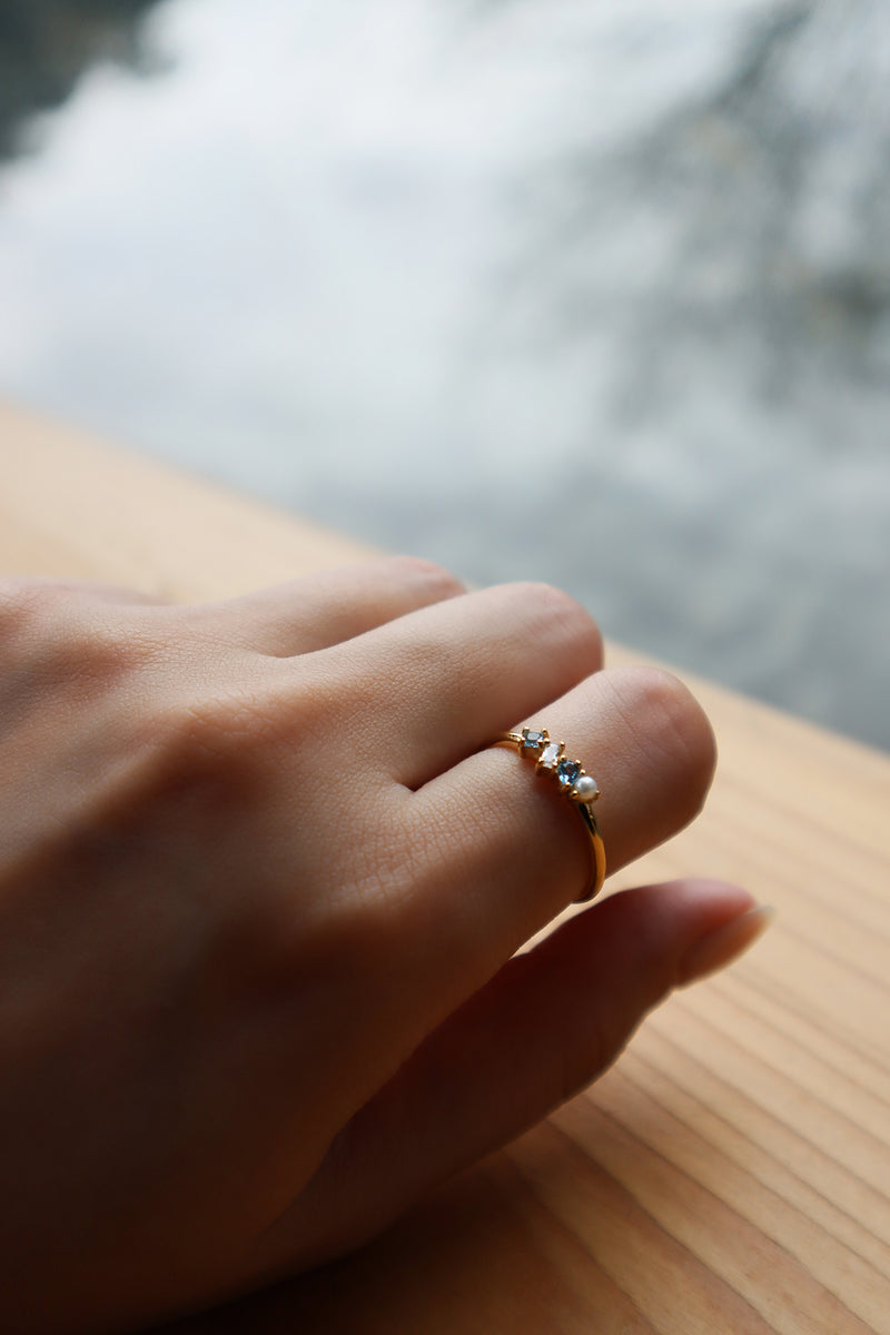 Assorted gemstones gold ring on index finger on wooden table