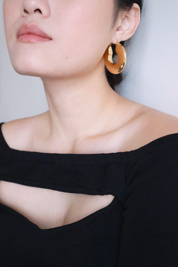 Woman in black dress wearing fashionable gold hoops for the night look